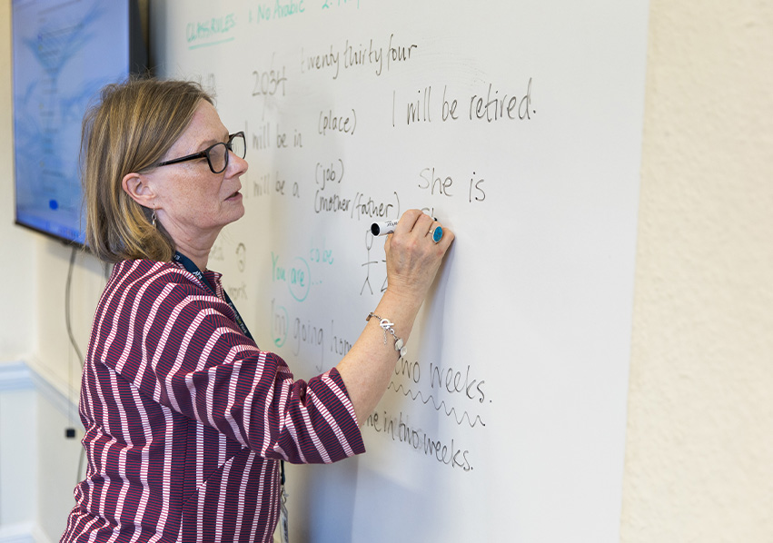 Professora escrevendo no quadro branco